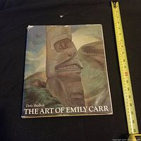 Full front cover view showing the dust jacket with a carved totem pole image. Ruler shown for size reference.