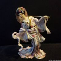 Front view of the porcelain figurine of a Japanese maiden in kimono holding a parasol, showing detailed painting and gold accents
