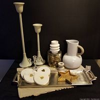 Photo showing white ceramic pitcher, tall white pillar candle holders of two sizes, textured white vase, gold star-shaped dish on a rectangular silver metal tray with handles. Two small white candle holders and clear glass candelabra included.