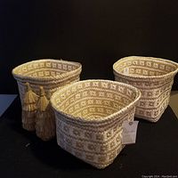 Three new woven planter baskets with cream and tan geometric pattern displayed with two attached tassels.