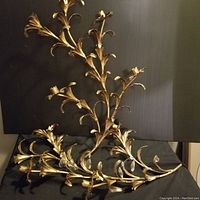 Two gilt metal floral wall decor pieces with crystal accents displayed on black background.