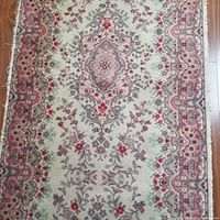 Close-up photo of the wool runner rug showing the central floral and medallion design with pink border and cream background.