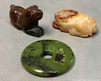 Three jade carved pendants displayed on grey background front view