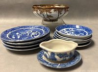 Image of blue and white miniature plates stacked with gravy boat on matching saucer and gold bamboo footed bowl behind