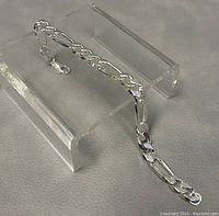 Photo of 8 inch Figaro style 925 silver bracelet on clear stand showing chain pattern and clasp.