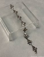 Photo showing full length of linked thistle motif bracelet on support stand.