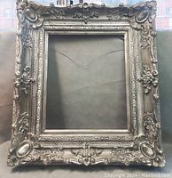 Front view of the large ornate French wooden frame showing detailed carvings and metallic finish.