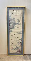 Full view of the framed Chinese print showing flying birds, flowers, rocks, and calligraphy, with blue and maroon matting and gold frame.