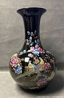 Front view of large Chinese floor vase showing full body and neck with floral and bird designs on a black background.
