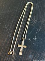 Chain and cross laid flat on dark wood surface