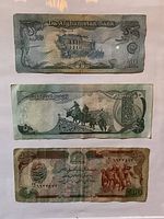 Close-up image of the three Afghan banknotes displayed vertically, showing details and condition of each note.