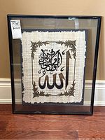 Full view of framed Arabic calligraphy on papyrus paper showing the entire framed piece including the beige natural papyrus sheet with black and brown calligraphy and floral decorations.