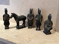Front view of all 5 Chinese terracotta warrior figurines and the horse figurine, arranged in a line, showing variety of postures and details.