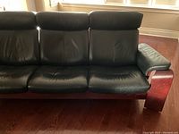 Front angle view of sofa showing three seats and wooden frame