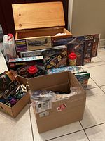 Wide shot of lot's contents showing wooden toy box behind and assorted set boxes and parts in front