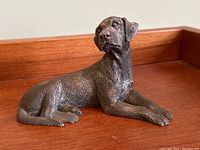 Front and side view of reclining dog figurine showing pose and overall detail