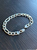 Full view of the sterling silver men's chain link bracelet with lobster claw clasp and heart-shaped stamped end link