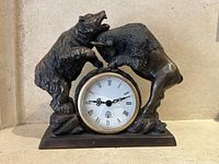 Front view of the bear and bull clock showing the bear on the left and bull on the right, with Roman numeral clock face in the center.