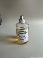 Front view of Maison Margiela Replica Beach Walk perfume bottle with visible label and amber perfume liquid inside.