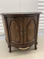 Front view of one wooden drum table or nightstand showing detailed door fronts, metal handles, and visible damage on the base.