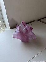 Pink art glass vase with swirls and folded edges viewed from an angle