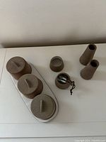 Photo of the set from an angle showing the condiment jars with lids on the tray, the two spice jars with spoons, and the two cone-shaped candleholders.