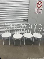 Four white vintage bentwood style chairs shown from front and side angles against a storage unit door.