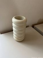 Front view of cream-colored soapstone vase with carved rounded bands ringed around the body and a hollow top opening.