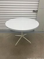 Full view of the white round dining table showing its overall shape and condition.