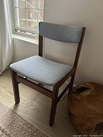 Front and side angle of vintage walnut chair showing blue striped upholstered padded seat and backrest with wooden frame
