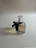 Front view of the perfume bottle showing overall design and velvet ribbon with YSL emblem.