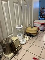 Food processor, blender, hand mixer, electric frying pan, crockpot grouped on floor, showing overall lot contents.