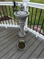 Full view of the tall pedestal water fountain with bird figurines on top next to the bird bath basin on deck