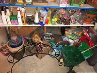 Shelves stocked with various gardening supplies including bottles, bags of soil and fertilizer, jars and small bags of gardening materials, some pots and plant holders on the floor.