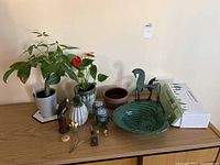 View of entire lot showing plants, candles, metal horse sculptures, bird figurines, ceramic pottery, and LED grow light set box