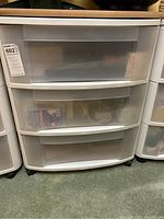 Front view of white plastic storage drawers showing three translucent drawers on wheels