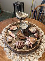 Photo showing entire woven tray with ceramic turtle, shells and starfish on top, arranged decoratively on a wooden table with lace tablecloth underneath