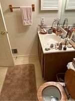 Overall view of bathroom sink area showing bath towels, wood birds, shell decoration on counter and brown rug on floor.