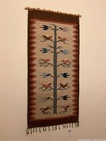 Full view of woven tapestry hung on wall showing entire design and fringed bottom.