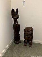 Full view of both sculptures side by side in corner, showing size comparison and condition