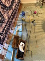 Photo showing three decorative metal garden stakes with glass orbs and hand design, two metal planter boxes, and gardening tools.