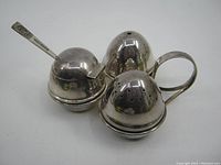 Angora silverplate cruet set showing salt shaker, pepper shaker, mustard pot with lid and matching spoon from side angle on white background