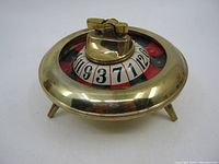 Top-front angled view of the brass roulette wheel lighter showing the lighter mechanism and numbered wheel.