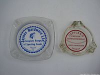 Both ashtrays together showing size and shape differences, labels distinct.