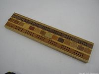 Full top view of the rectangular cribbage board showing the multiple wood species and scoring holes.