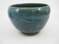 Front angled view of the handmade studio pottery bowl showing the blue-green glazed surface and rounded shape.