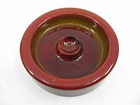 Top view showing the deep center and circular raised cigarette holder with rich red glass color and slight wear marks.