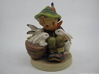 Front view of M.J. Hummel figurine showing boy with rabbits and basket.