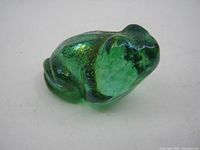 Top and side view showing the green translucent glass frog paperweight with textured and mottled internal coloring.