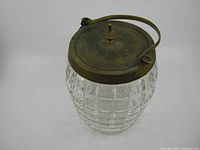 Overall view of the Victorian cut glass biscuit jar with metal lid and handle showing the faceted cut glass body and metal lid with handle.